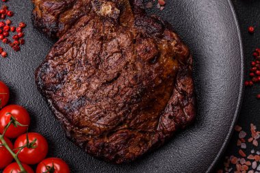 Tuz, baharat ve otlarla ızgarada kızartılmış lezzetli biftekli biftek ve çimento arka planda.