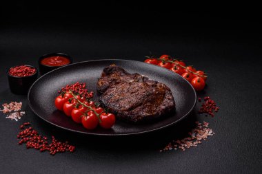 Tuz, baharat ve otlarla ızgarada kızartılmış lezzetli biftekli biftek ve çimento arka planda.