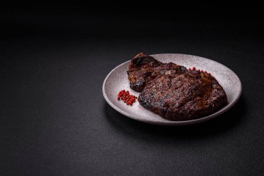 Tuz, baharat ve otlarla ızgarada kızartılmış lezzetli biftekli biftek ve çimento arka planda.