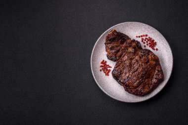 Tuz, baharat ve otlarla ızgarada kızartılmış lezzetli biftekli biftek ve çimento arka planda.