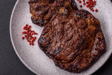 Tuz, baharat ve otlarla ızgarada kızartılmış lezzetli biftekli biftek ve çimento arka planda.