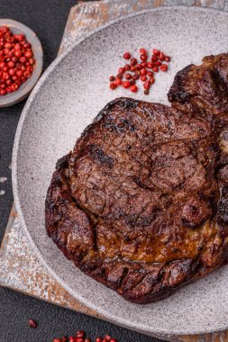 Tuz, baharat ve otlarla ızgarada kızartılmış lezzetli biftekli biftek ve çimento arka planda.