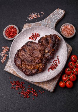 Tuz, baharat ve otlarla ızgarada kızartılmış lezzetli biftekli biftek ve çimento arka planda.