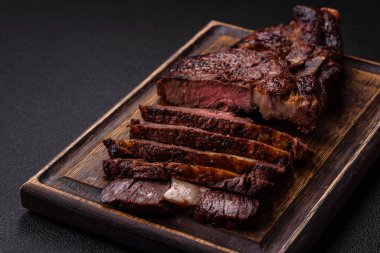 Tuz, baharat ve otlarla ızgarada kızartılmış lezzetli biftekli biftek ve çimento arka planda.