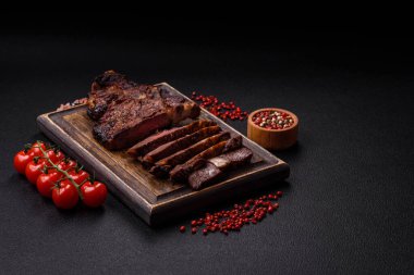 Tuz, baharat ve otlarla ızgarada kızartılmış lezzetli biftekli biftek ve çimento arka planda.