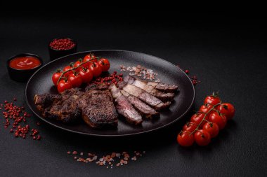 Tuz, baharat ve otlarla ızgarada kızartılmış lezzetli biftekli biftek ve çimento arka planda.