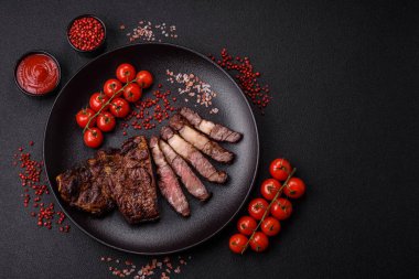 Tuz, baharat ve otlarla ızgarada kızartılmış lezzetli biftekli biftek ve çimento arka planda.