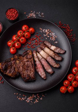 Tuz, baharat ve otlarla ızgarada kızartılmış lezzetli biftekli biftek ve çimento arka planda.