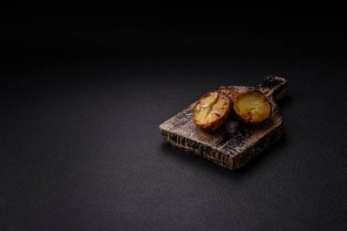 Tuz, baharat ve otlarla kızartılmış, koyu beton bir arka planda lezzetli yarım patatesler.