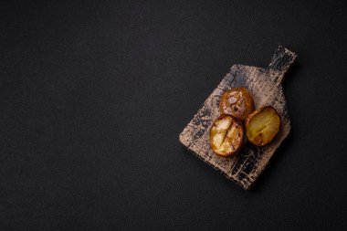 Tuz, baharat ve otlarla kızartılmış, koyu beton bir arka planda lezzetli yarım patatesler.