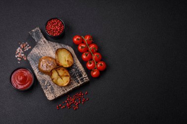 Tuz, baharat ve otlarla kızartılmış, koyu beton bir arka planda lezzetli yarım patatesler.