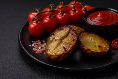 Tuz, baharat ve otlarla kızartılmış, koyu beton bir arka planda lezzetli yarım patatesler.