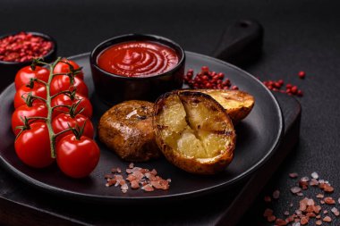 Tuz, baharat ve otlarla kızartılmış, koyu beton bir arka planda lezzetli yarım patatesler.