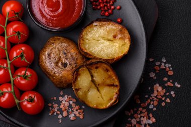 Tuz, baharat ve otlarla kızartılmış, koyu beton bir arka planda lezzetli yarım patatesler.