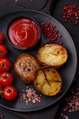 Tuz, baharat ve otlarla kızartılmış, koyu beton bir arka planda lezzetli yarım patatesler.