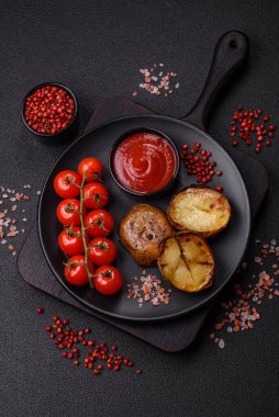 Tuz, baharat ve otlarla kızartılmış, koyu beton bir arka planda lezzetli yarım patatesler.