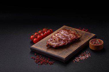 Izgarada pişmiş lezzetli ızgara pirzola, tuzlu, baharatlı ve çimento kaplı bir arka planda otlar.