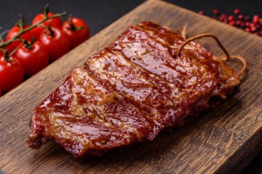 Izgarada pişmiş lezzetli ızgara pirzola, tuzlu, baharatlı ve çimento kaplı bir arka planda otlar.