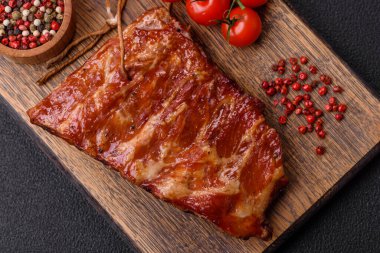 Izgarada pişmiş lezzetli ızgara pirzola, tuzlu, baharatlı ve çimento kaplı bir arka planda otlar.