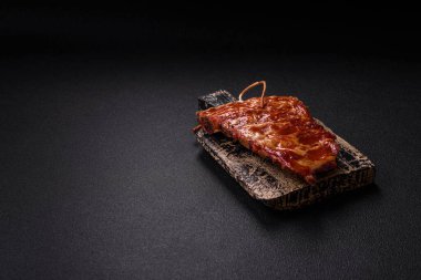 Izgarada pişmiş lezzetli ızgara pirzola, tuzlu, baharatlı ve çimento kaplı bir arka planda otlar.