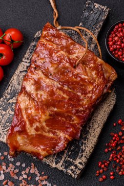 Izgarada pişmiş lezzetli ızgara pirzola, tuzlu, baharatlı ve çimento kaplı bir arka planda otlar.