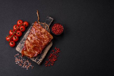 Izgarada pişmiş lezzetli ızgara pirzola, tuzlu, baharatlı ve çimento kaplı bir arka planda otlar.