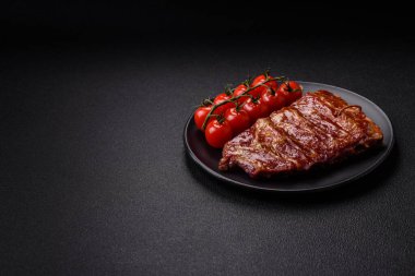 Izgarada pişmiş lezzetli ızgara pirzola, tuzlu, baharatlı ve çimento kaplı bir arka planda otlar.