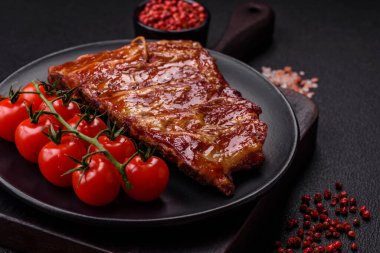 Izgarada pişmiş lezzetli ızgara pirzola, tuzlu, baharatlı ve çimento kaplı bir arka planda otlar.