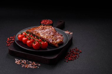 Izgarada pişmiş lezzetli ızgara pirzola, tuzlu, baharatlı ve çimento kaplı bir arka planda otlar.