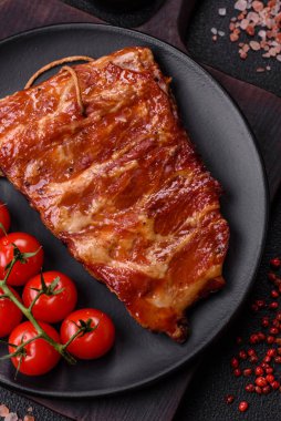 Izgarada pişmiş lezzetli ızgara pirzola, tuzlu, baharatlı ve çimento kaplı bir arka planda otlar.