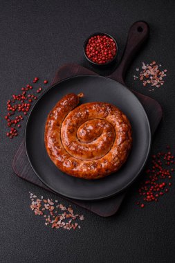 Izgarada, tuz, baharat ve otlarla pişirilmiş, koyu beton arka planda pişirilmiş nefis ev yapımı sosis.