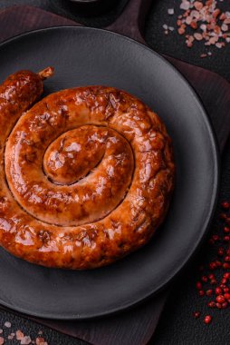 Izgarada, tuz, baharat ve otlarla pişirilmiş, koyu beton arka planda pişirilmiş nefis ev yapımı sosis.