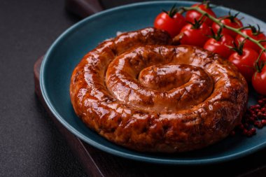 Izgarada, tuz, baharat ve otlarla pişirilmiş, koyu beton arka planda pişirilmiş nefis ev yapımı sosis.