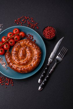 Izgarada, tuz, baharat ve otlarla pişirilmiş, koyu beton arka planda pişirilmiş nefis ev yapımı sosis.