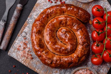 Izgarada, tuz, baharat ve otlarla pişirilmiş, koyu beton arka planda pişirilmiş nefis ev yapımı sosis.