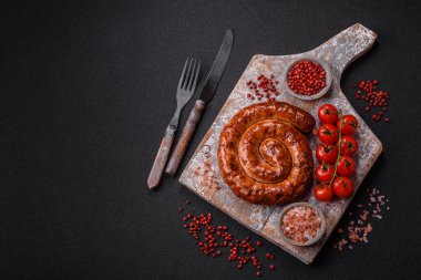 Izgarada, tuz, baharat ve otlarla pişirilmiş, koyu beton arka planda pişirilmiş nefis ev yapımı sosis.