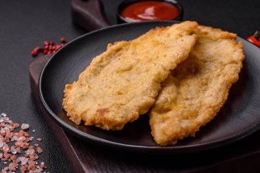 Lezzetli, sulu tavuk pirzolası, tuzlu, baharatlı ve çimento kaplı arka planda otlarla.