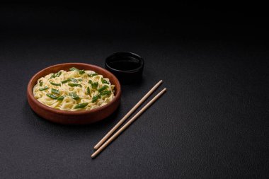 Lezzetli Asya mutfağı. İçinde pirinç, erişte, biber, mantar ve baharatlar var. Koyu beton arka planda.