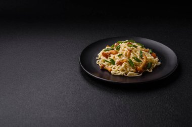 Lezzetli Asya mutfağı. İçinde pirinç, erişte, biber, mantar ve baharatlar var. Koyu beton arka planda.