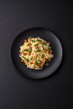 Lezzetli Asya mutfağı. İçinde pirinç, erişte, biber, mantar ve baharatlar var. Koyu beton arka planda.