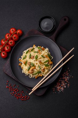 Lezzetli Asya mutfağı. İçinde pirinç, erişte, biber, mantar ve baharatlar var. Koyu beton arka planda.