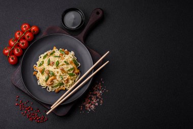 Lezzetli Asya mutfağı. İçinde pirinç, erişte, biber, mantar ve baharatlar var. Koyu beton arka planda.