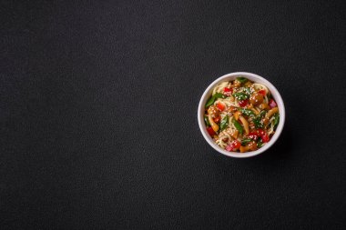 Lezzetli Asya mutfağı. İçinde pirinç, erişte, biber, mantar ve baharatlar var. Koyu beton arka planda.