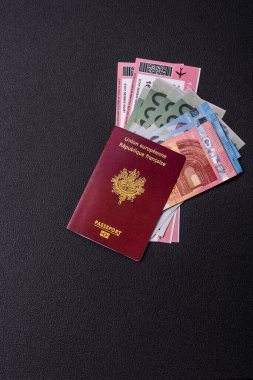 Fransa Cumhuriyeti pasaportu, uçak biletleri ve koyu beton arka planda para. Turizm ve seyahat teması üzerine kavramsal arka plan