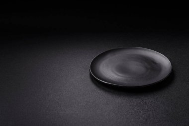 Empty ceramic round plate on dark textured concrete background. Cutlery, preparation for dinner