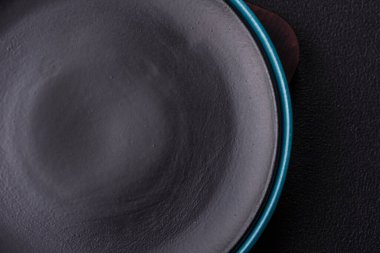 Empty ceramic round plate on dark textured concrete background. Cutlery, preparation for dinner