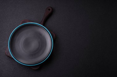 Empty ceramic round plate on dark textured concrete background. Cutlery, preparation for dinner