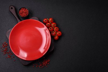 Empty ceramic round plate on dark textured concrete background. Cutlery, preparation for dinner