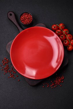 Empty ceramic round plate on dark textured concrete background. Cutlery, preparation for dinner