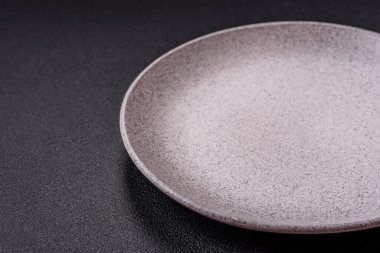 Empty ceramic round plate on dark textured concrete background. Cutlery, preparation for dinner